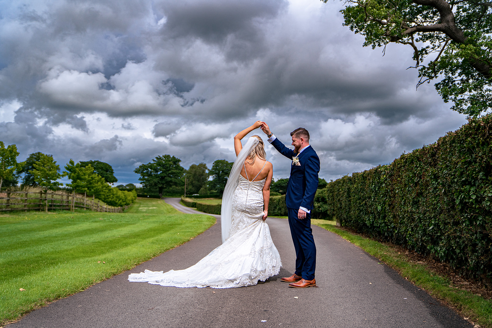 Lauren and Gavin together on the path at Sandhole Oak Barn beneath a cloudy summer sky